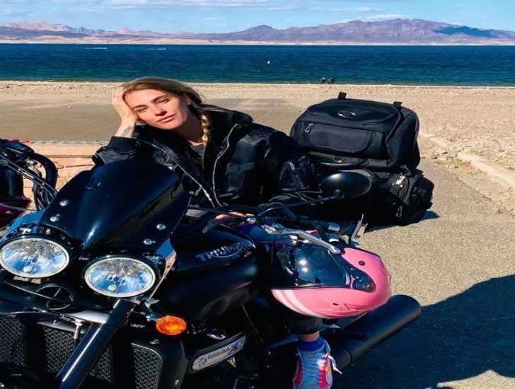 Candace Kroslak in a black jacket on her bike with pink helmet.
